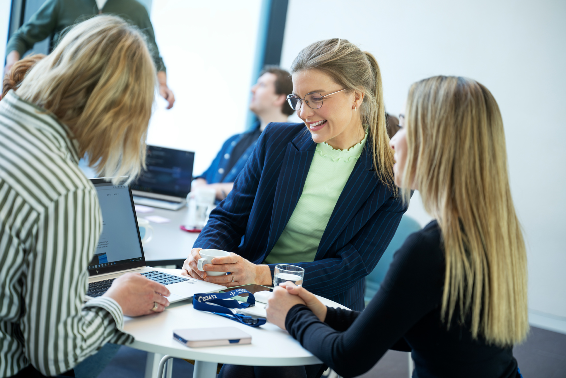 En gruppe mennesker som sitter ved et bord og ser på en bærbar datamaskin