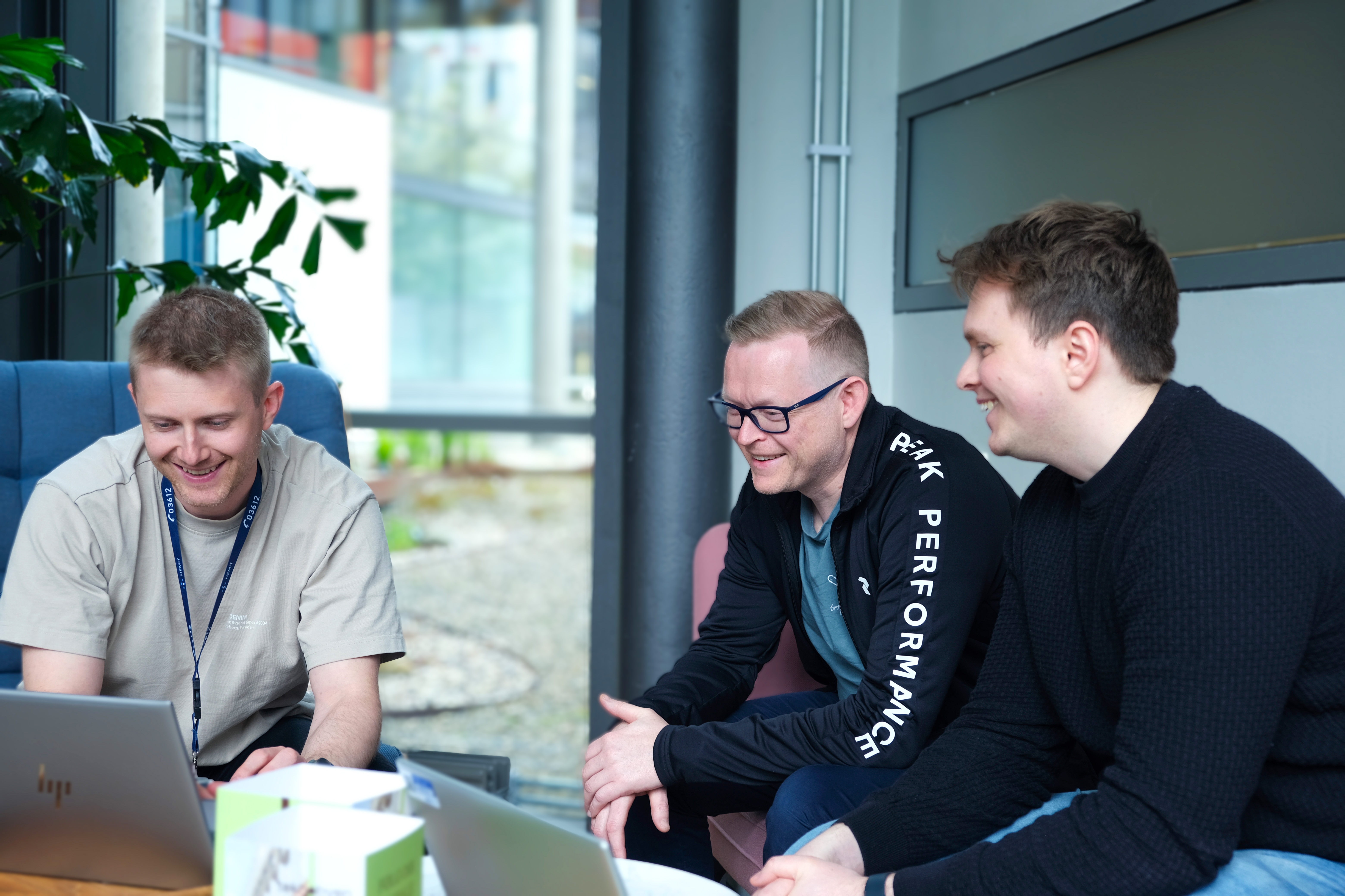 En gruppe menn som sitter rundt et bord med bærbare datamaskiner