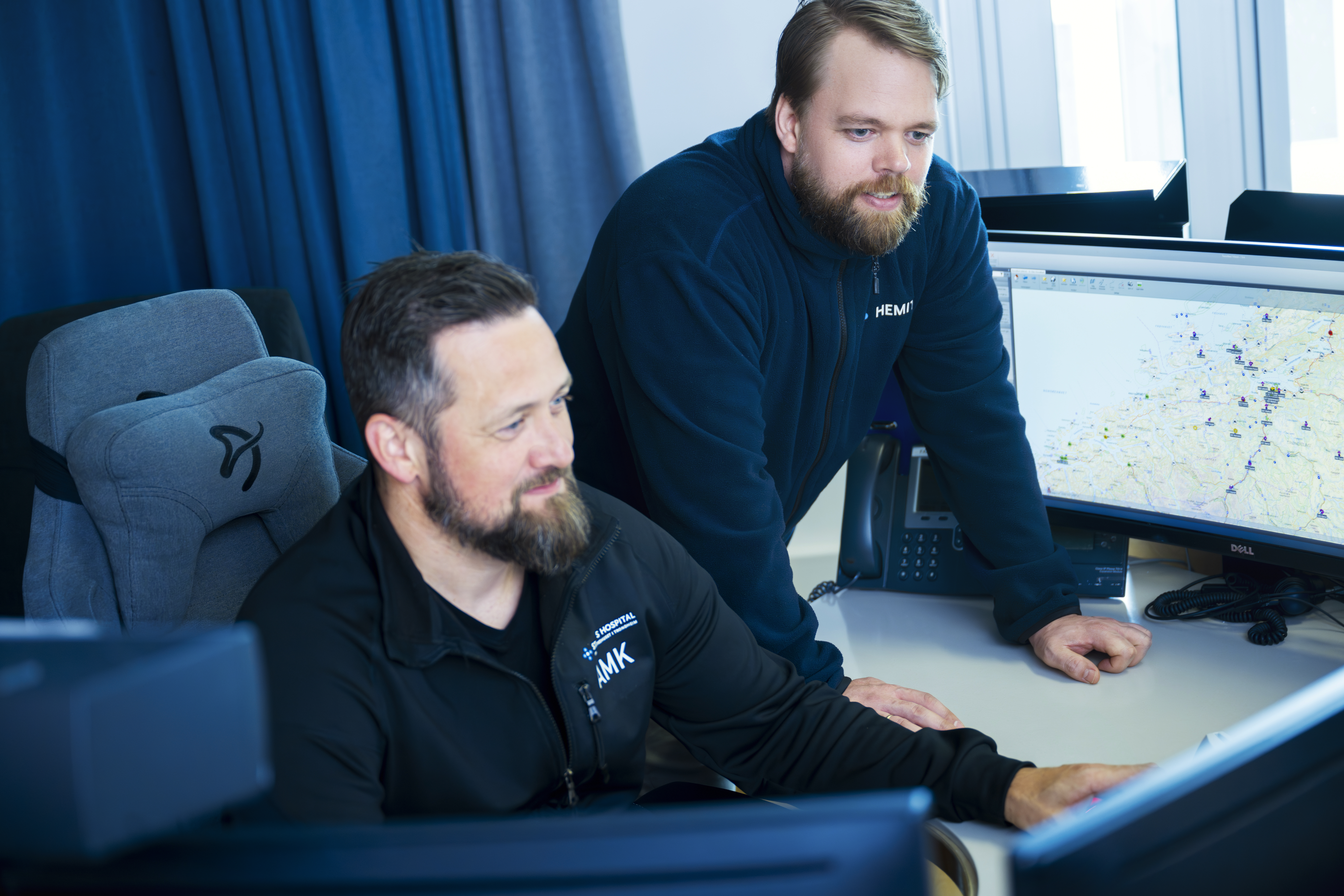 To Hemit ansatte ser på pc skjermer