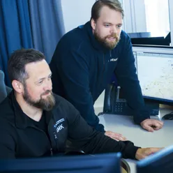 To Hemit ansatte ser på pc skjermer