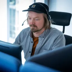 En mann med caps og hodetelefoner sittende i en stol