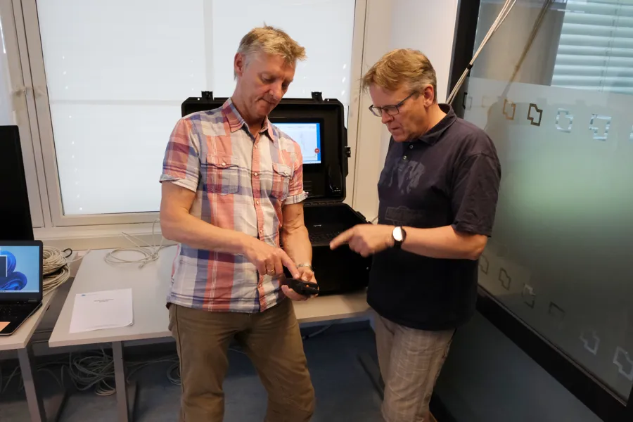 To Hemit ansatte snakker sammen om hvordan de skal bruke testutstyret på testrommet
