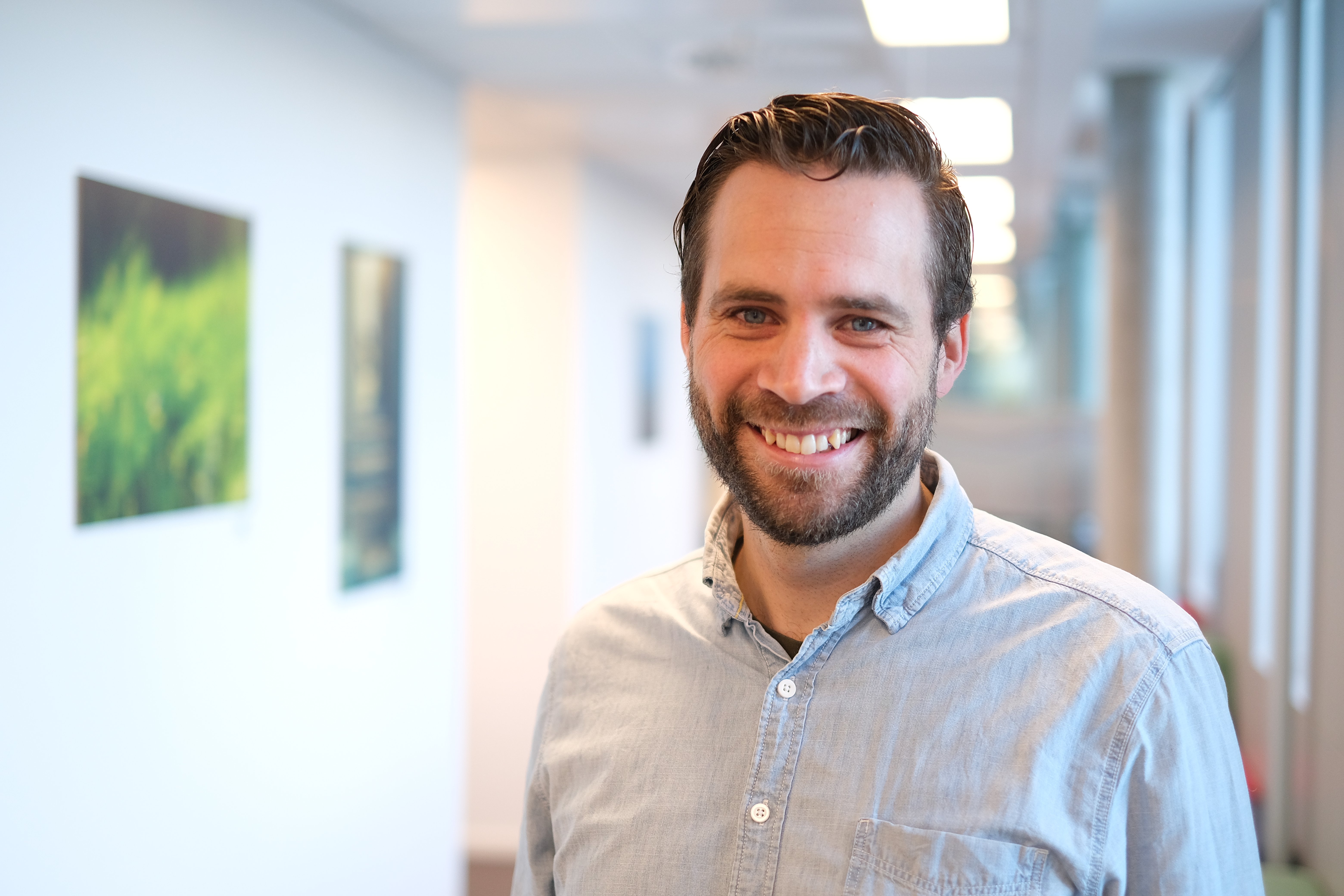 Smilende mann i kontorlandskap i Hemit