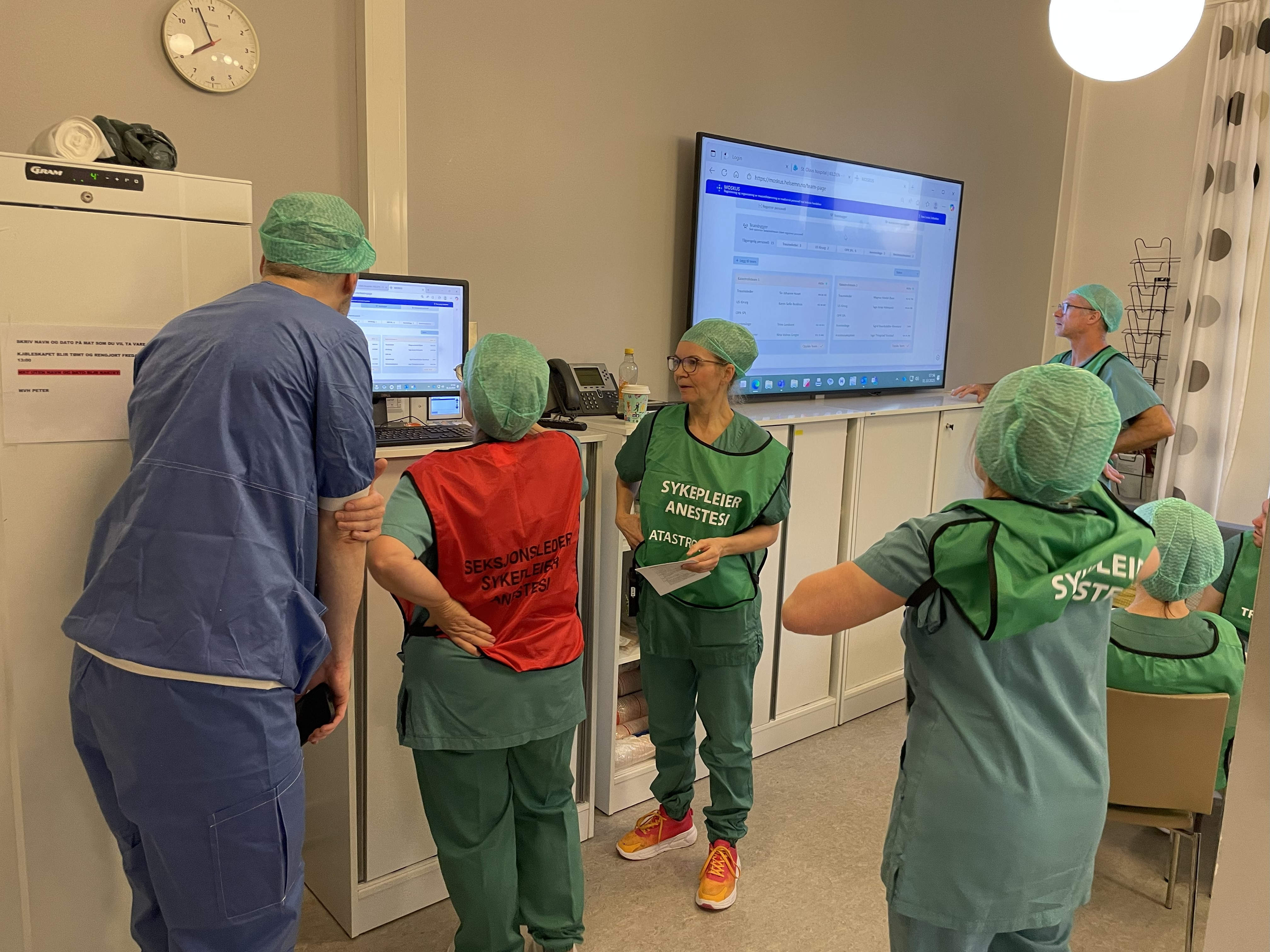 En gruppe mennesker på sykehus som ser på en skjerm under en beredskapsøvelse