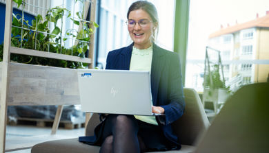 En person som sitter på en stol med en bærbar datamaskin